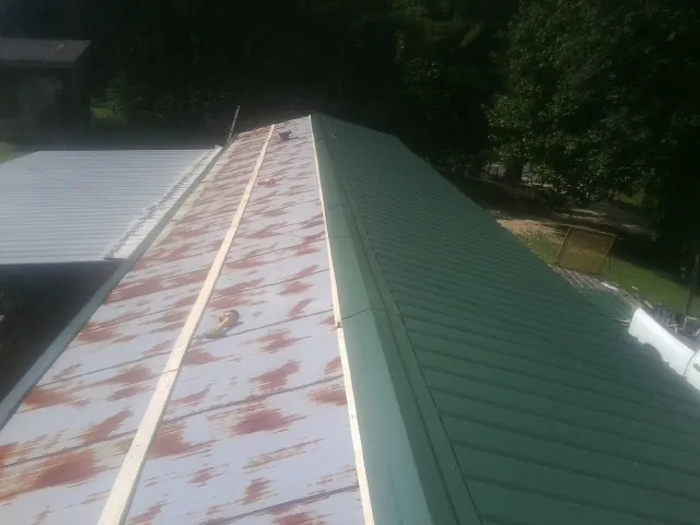 Old rusted panels beside newly installed green metal roofing — Wind Damage Roof Repair by Roofing Brothers in Spring House