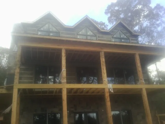 Dormers and porch framing on a large log home under construction — Roof Coating work by our crew in Spring House