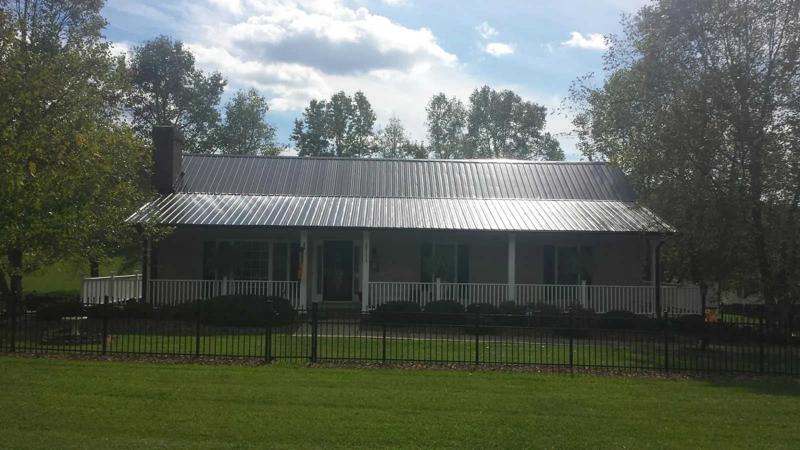 Gray metal roof on a brick ranch with a full width front porch — Gutter Guard Installation work by our crew in Spring House