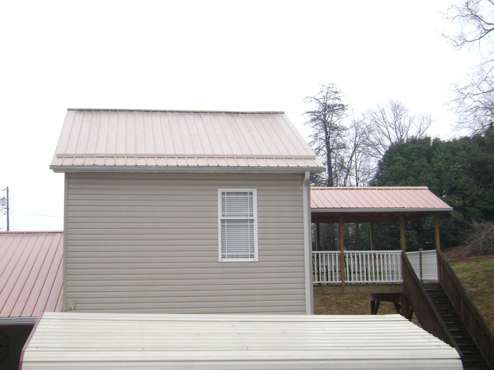 Tan metal roofs on a two story addition and attached porch, from a Roof Replacement job in Spring House
