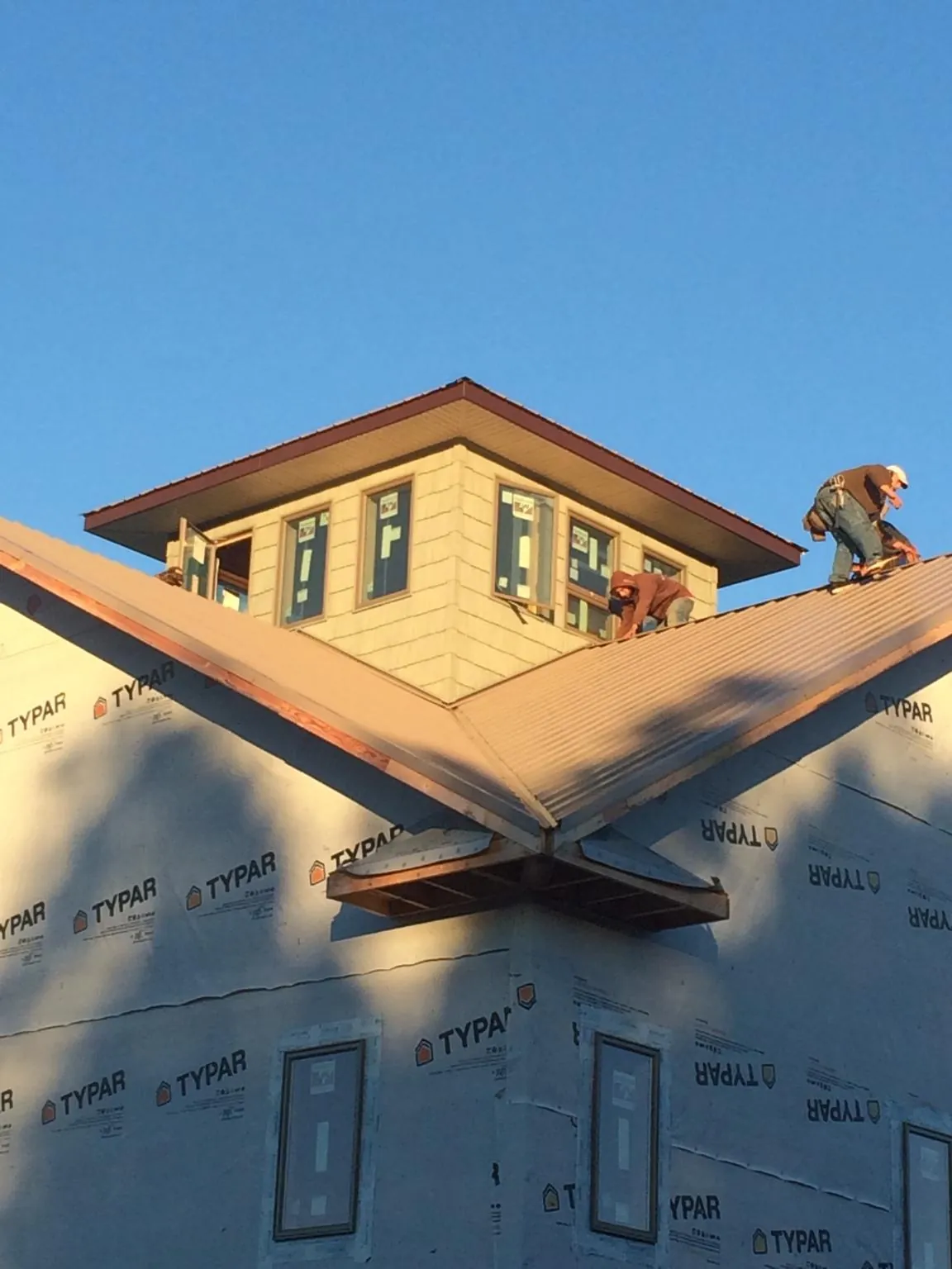 Roofers working around a rooftop cupola on a new metal roof at sunset — Roof Waterproofing in Spring House by Roofing Brothers